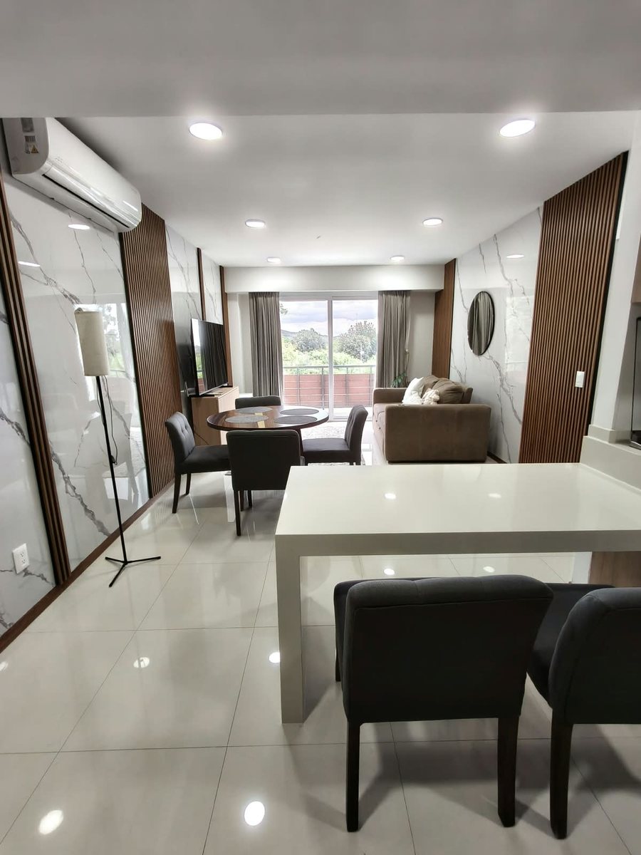 Sala y comedor amueblados con barra y ventanal hacia el balcón