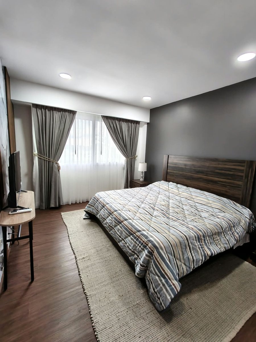 Recámara principal con cama matrimonial, pantalla y cortinas