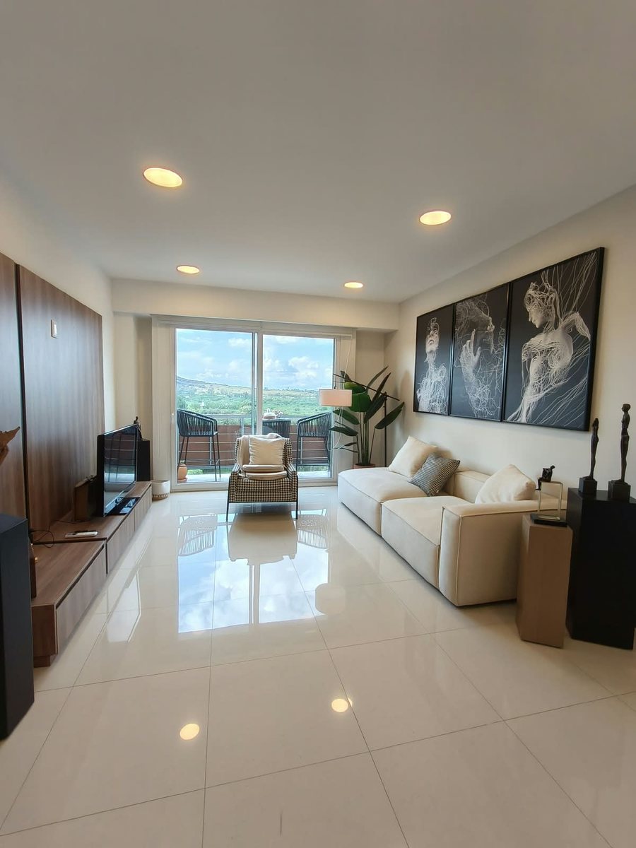 Sala con sillón, pantalla y ventanal hacia el balcón