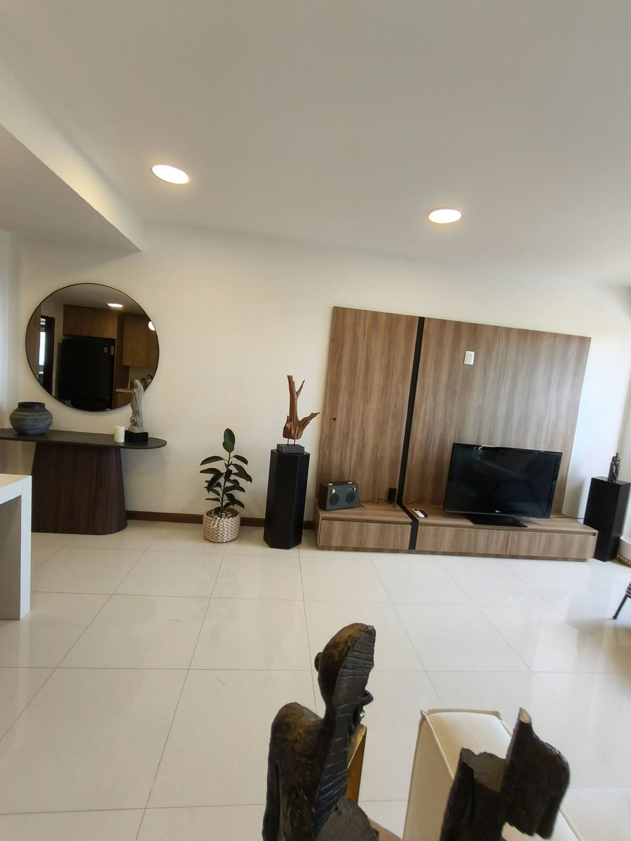 Sala con mueble de TV, espejo redondo y acceso al comedor