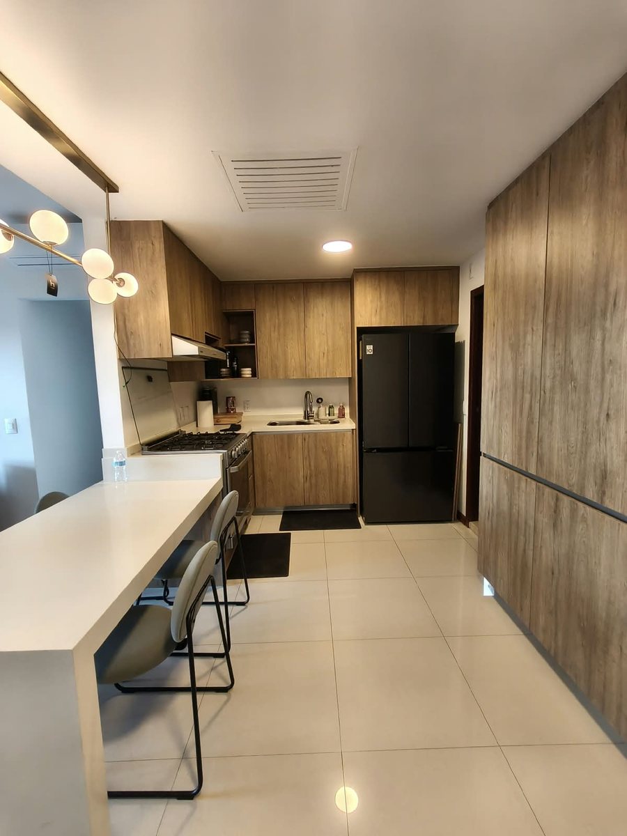 Cocina integral con barra, alacenas de madera y refrigerador