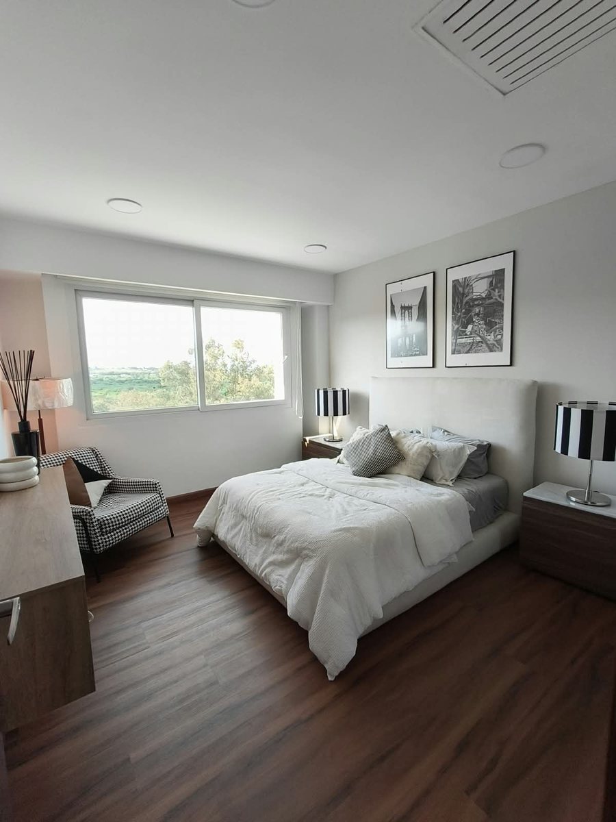 Recámara principal con cama matrimonial, sillón y ventana