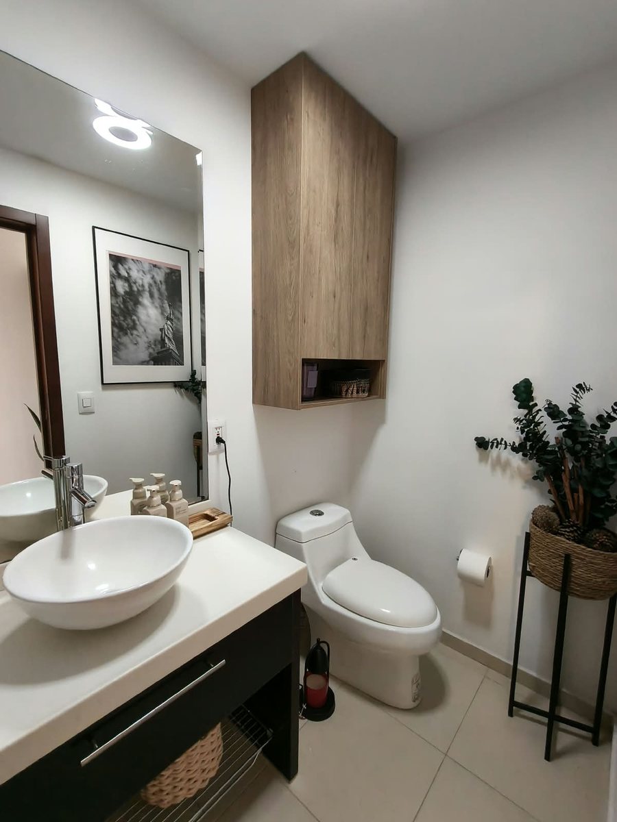 Baño con lavabo de cerámica, mueble de madera y sanitario