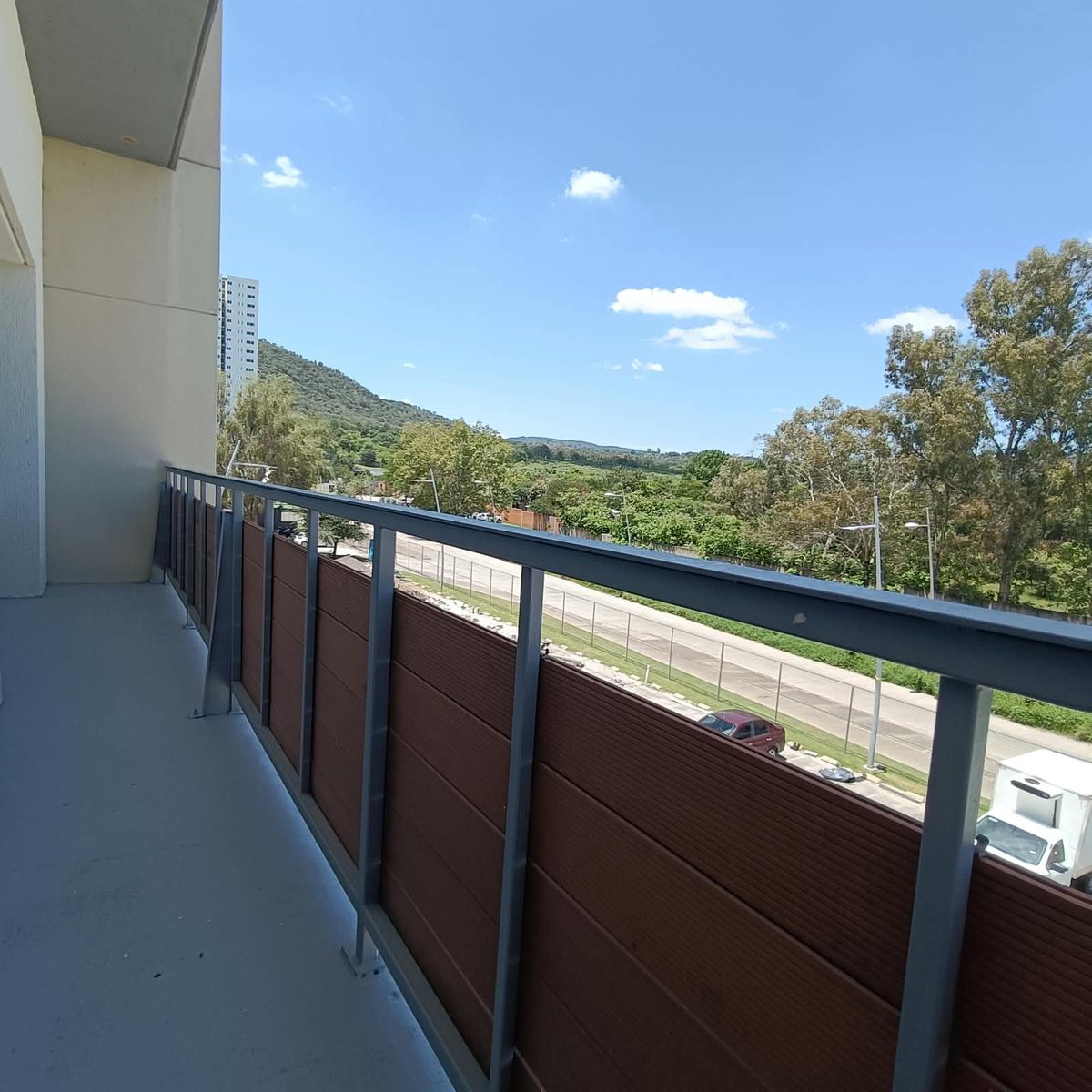 Balcón con barandal y vista a los árboles y los cerros