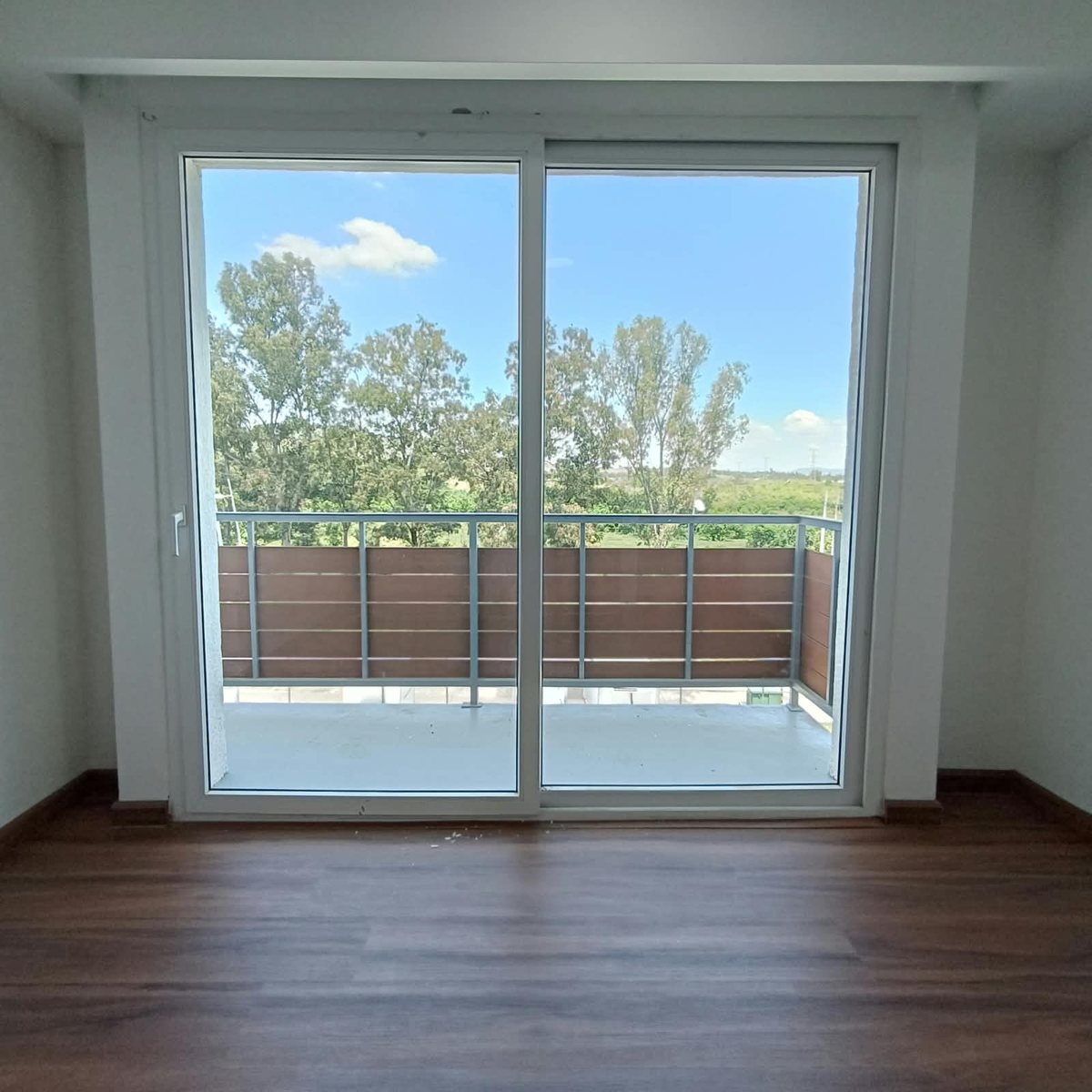 Recámara principal con piso de madera y puerta corrediza al balcón