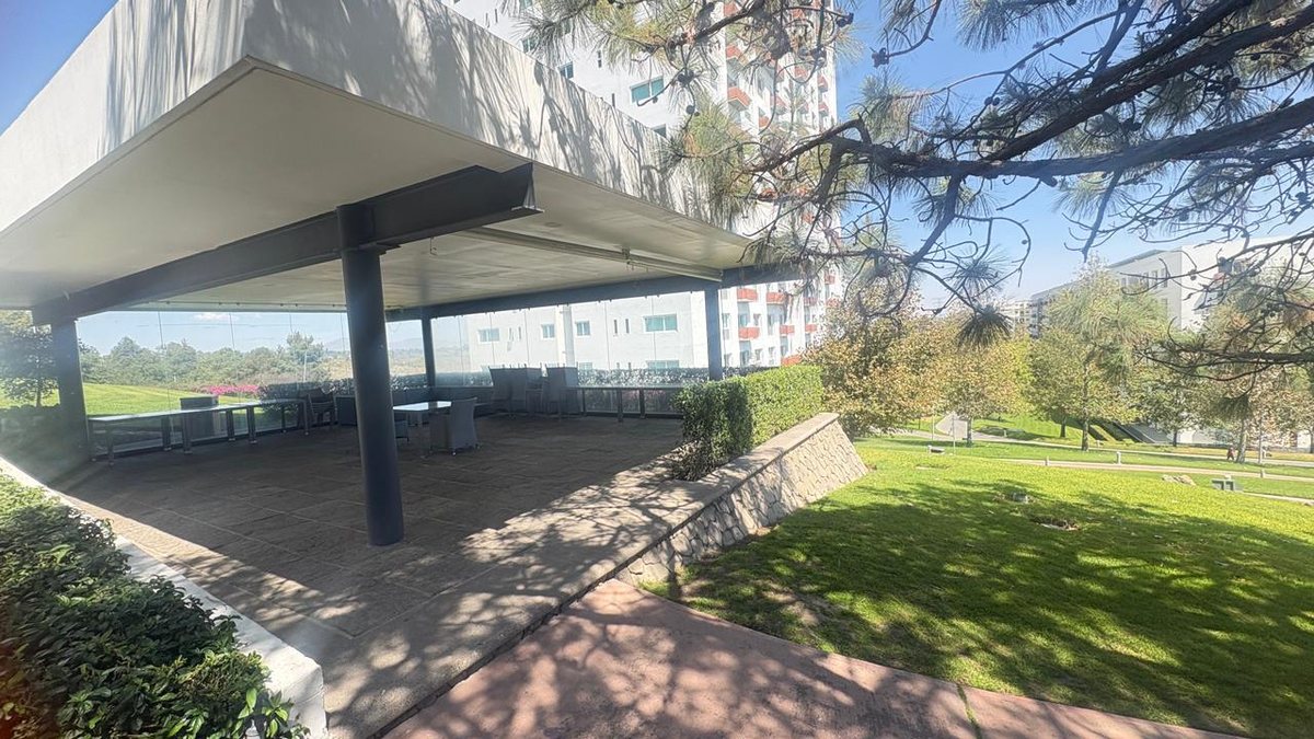Terraza techada con mesas junto al jardín