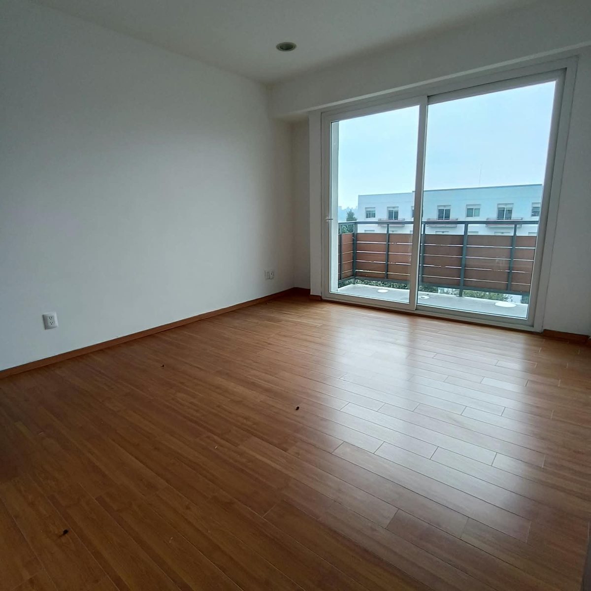 Recámara con piso de madera y puerta corrediza al balcón