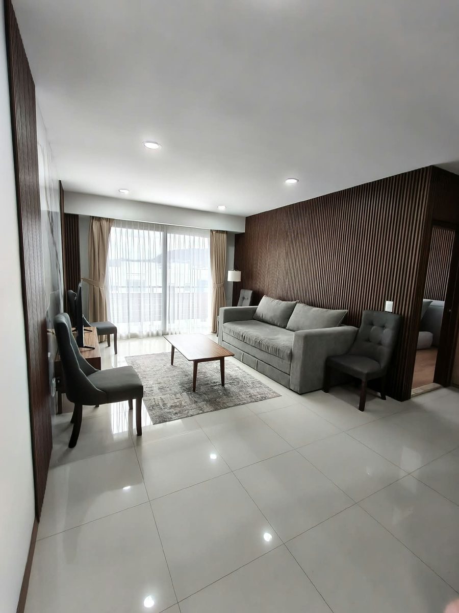 Sala amueblada con sillón, sillas y ventanal hacia el balcón