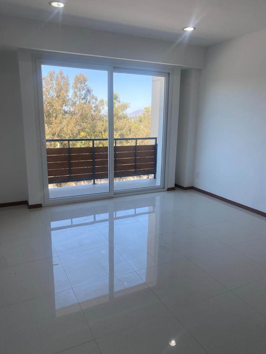 Sala con ventanal y balcón con vista a los árboles
