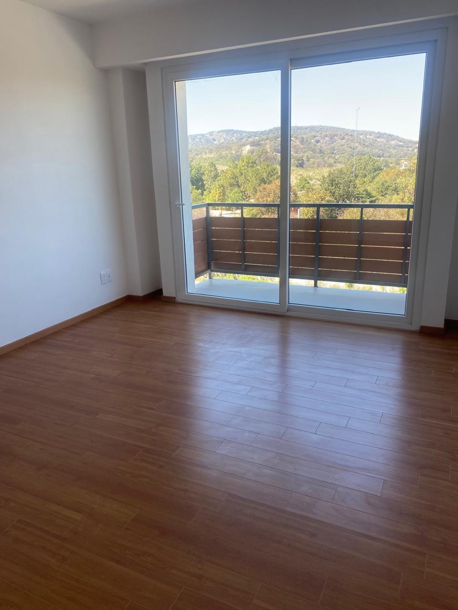 Recámara principal con piso de madera y puerta corrediza al balcón