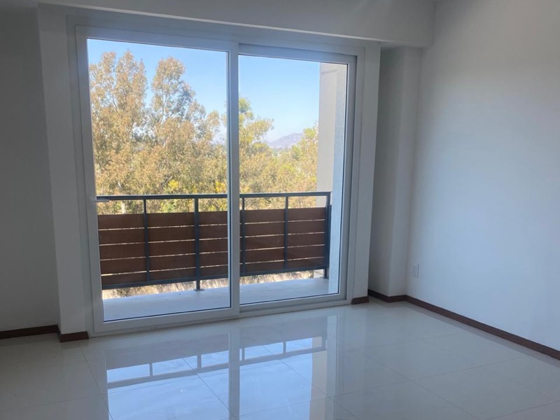 Sala con ventanal y balcón con vista a los árboles