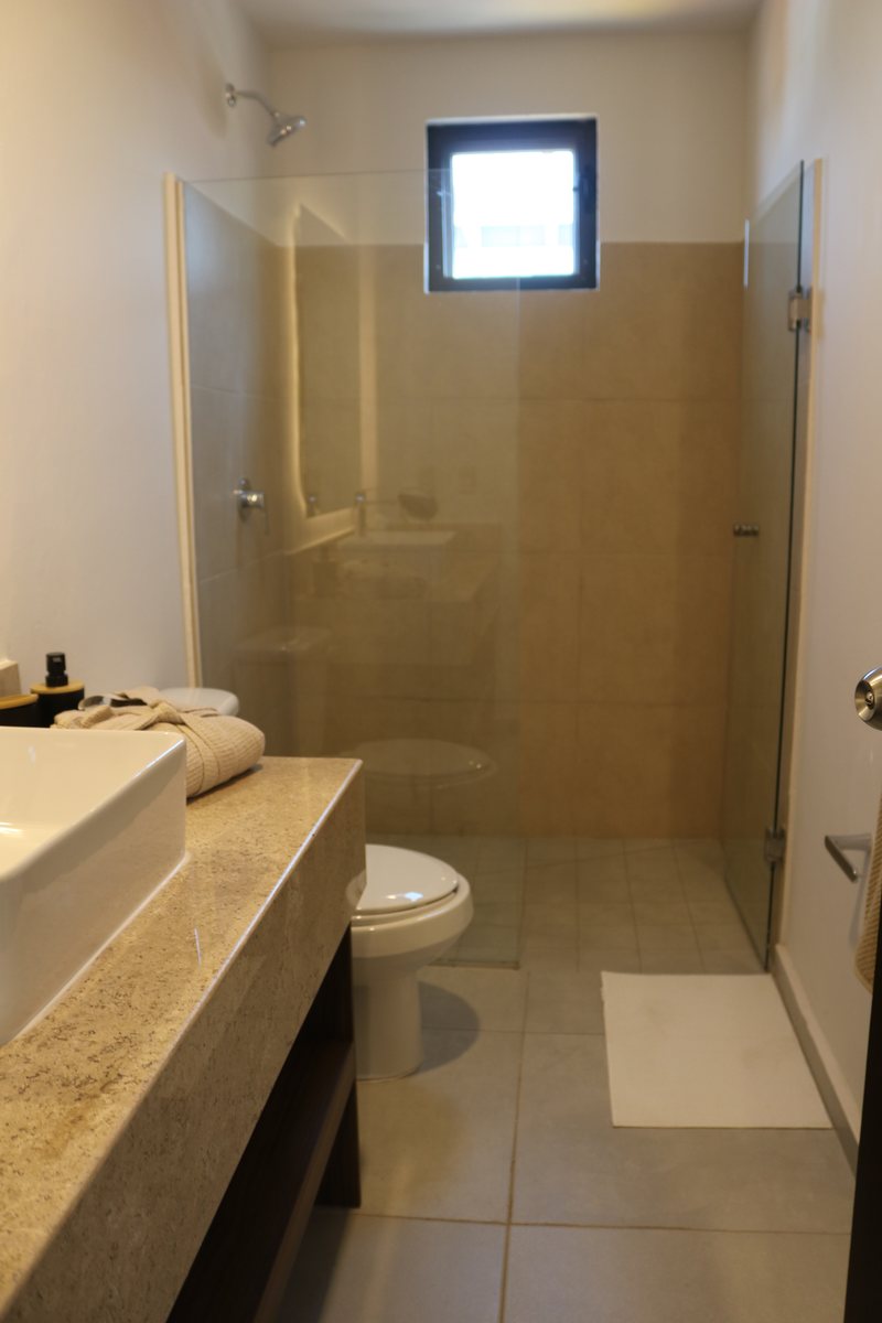 Baño con cancel de cristal en la casa muestra
