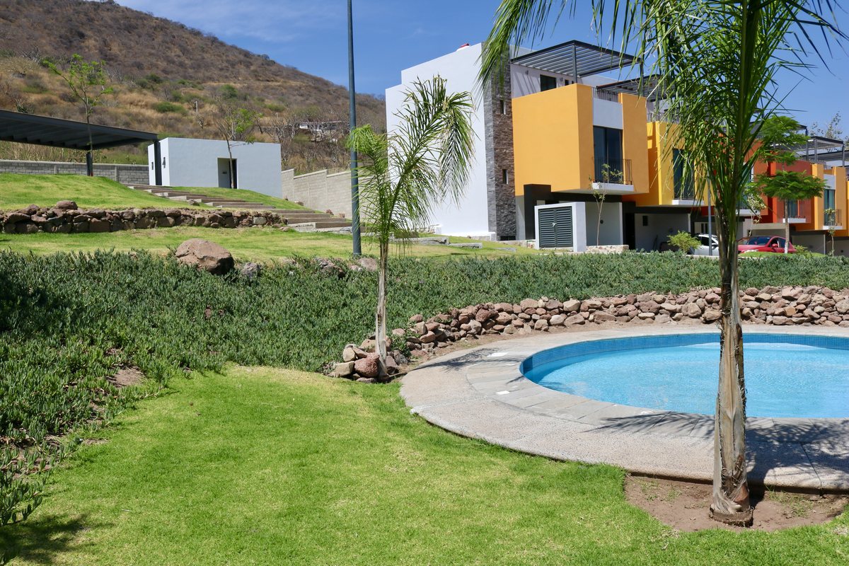 Alberca del coto rodeada de jardín, con el cerro al fondo