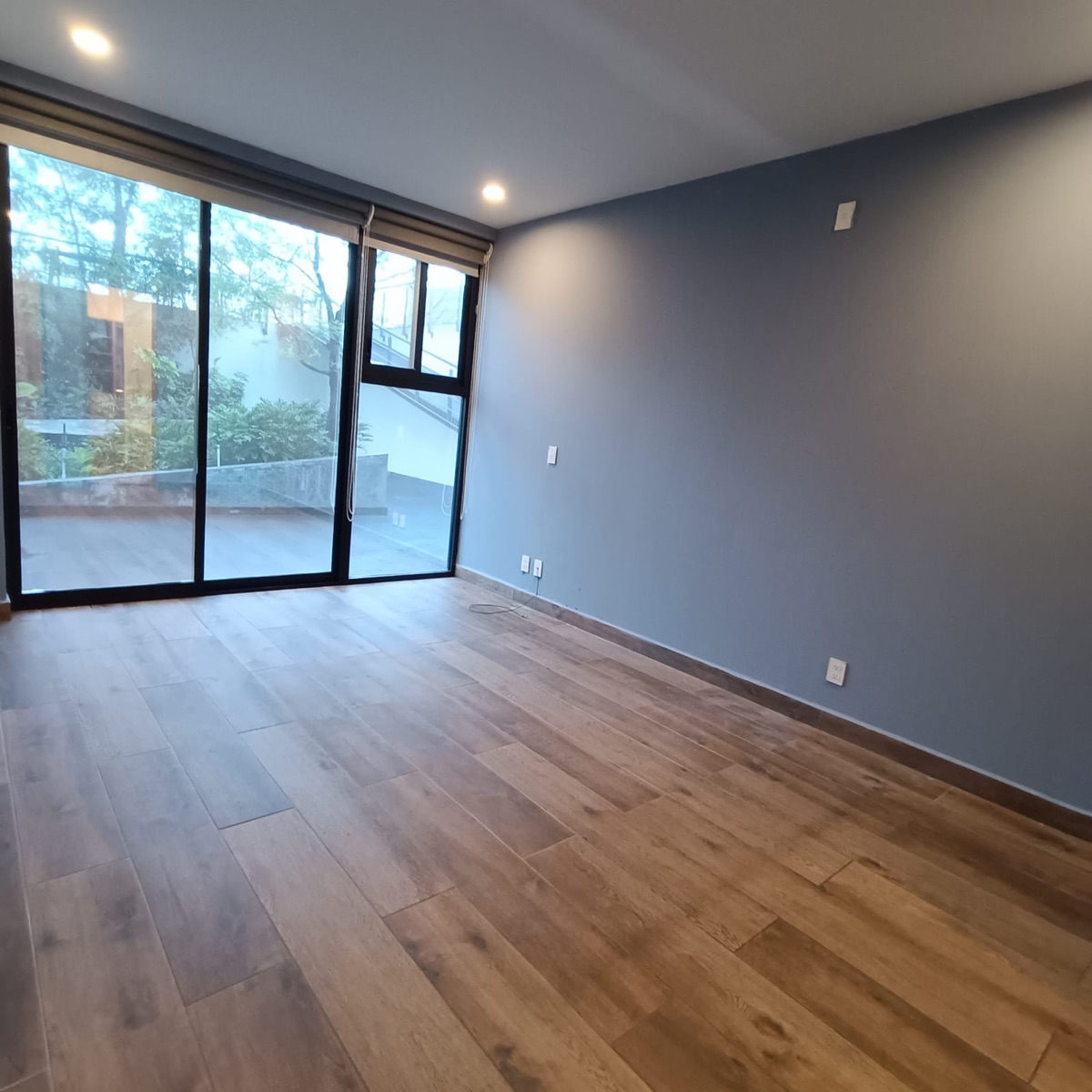 Recámara con piso de madera y ventanal corredizo hacia el exterior