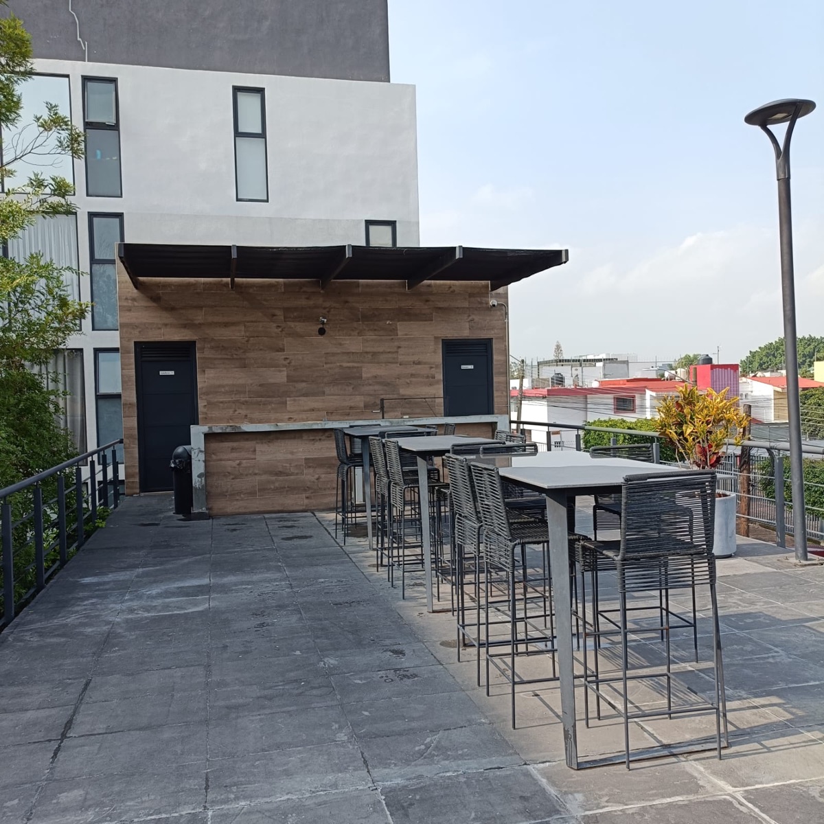 Terraza común con mesas altas y bancos