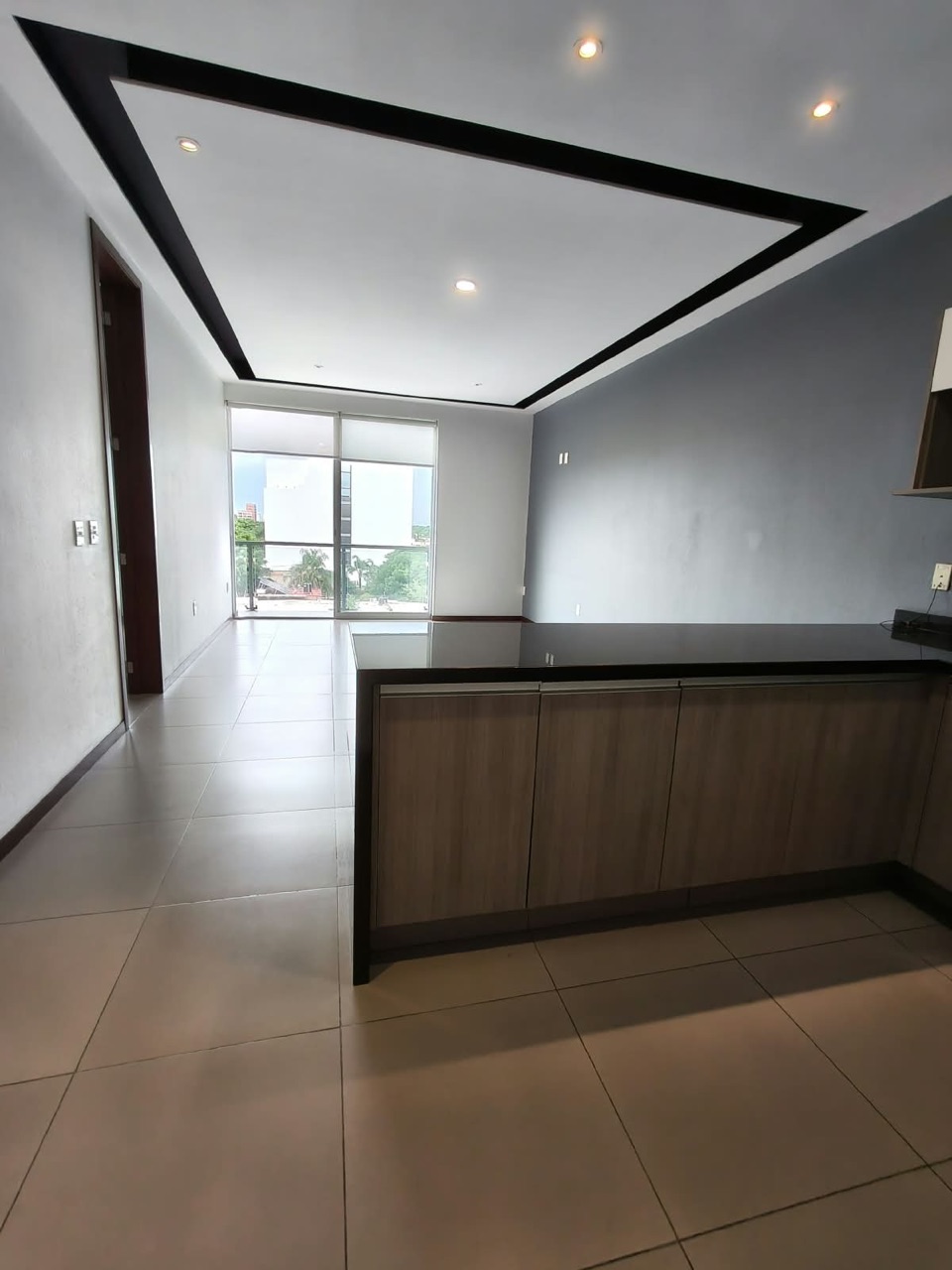 Sala y comedor con plafón de doble altura y ventanal hacia el balcón