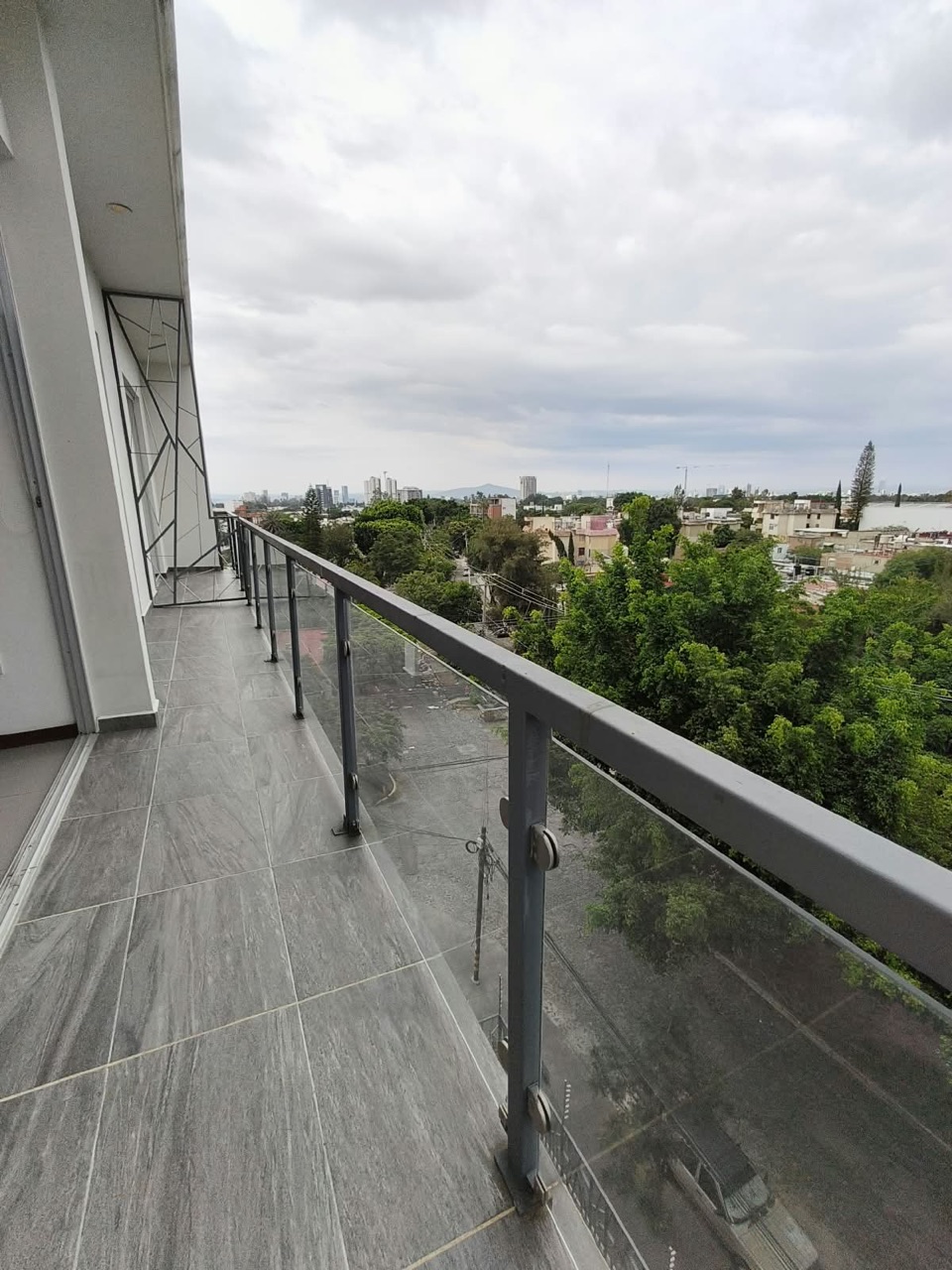 Balcón amplio con barandal de cristal y vista panorámica