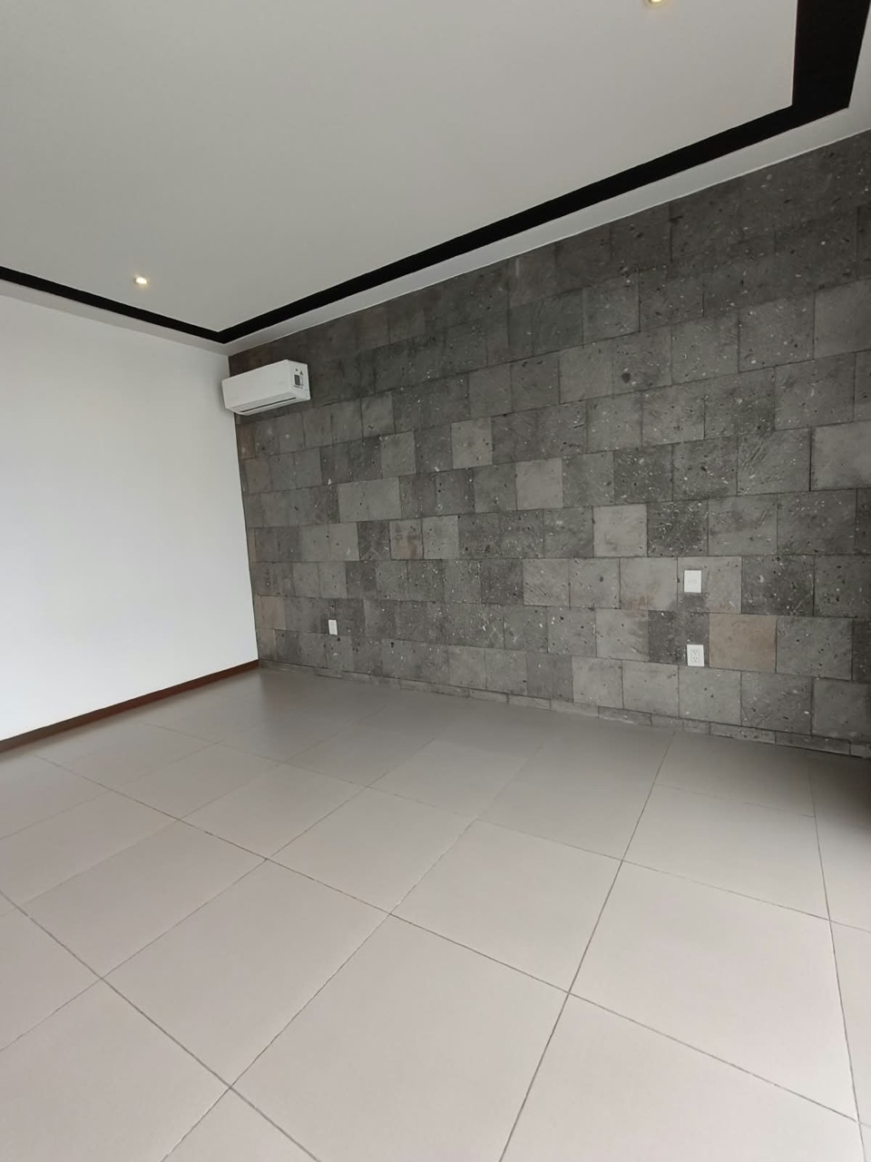 Recámara principal con muro de piedra y aire acondicionado