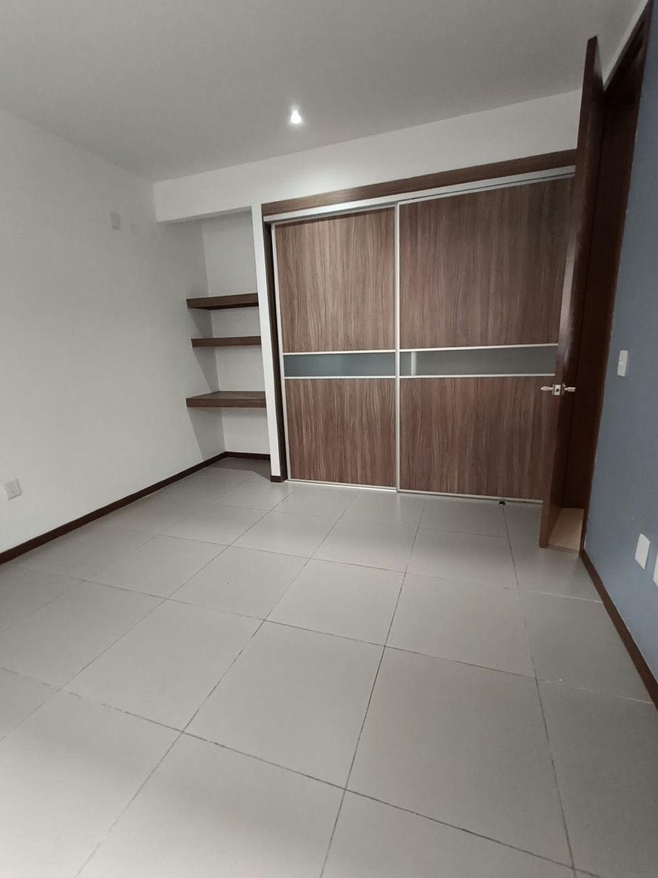 Recámara con clóset de puertas corredizas y repisas
