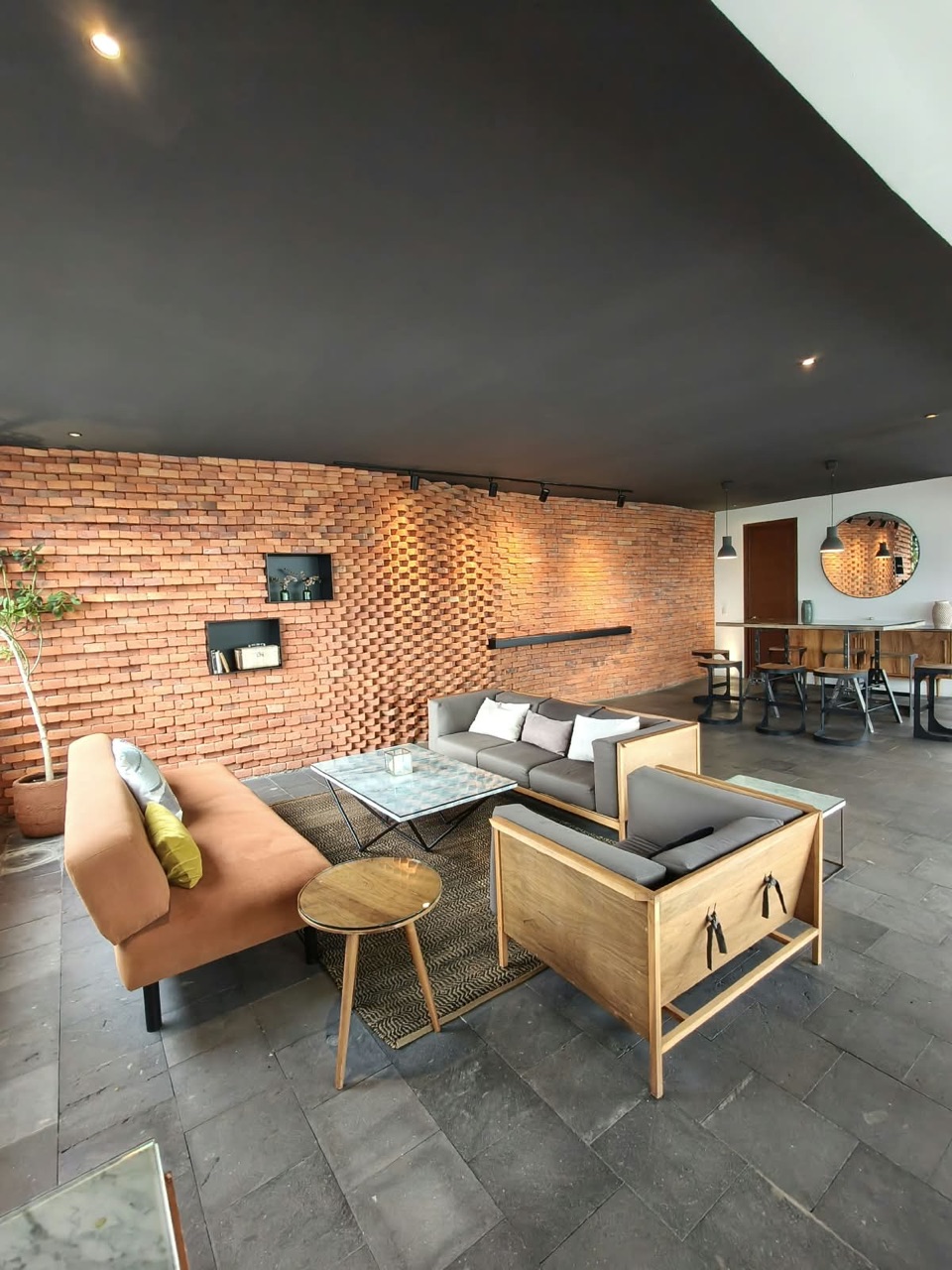 Área de coworking y sala de estar con muro de ladrillo