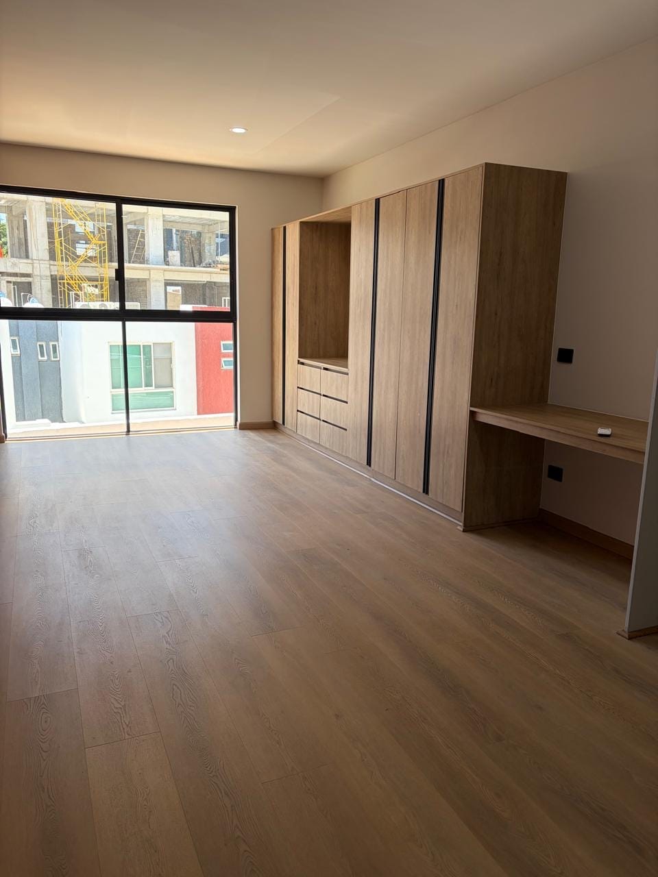 Estudio con ventanal, clóset de madera y escritorio