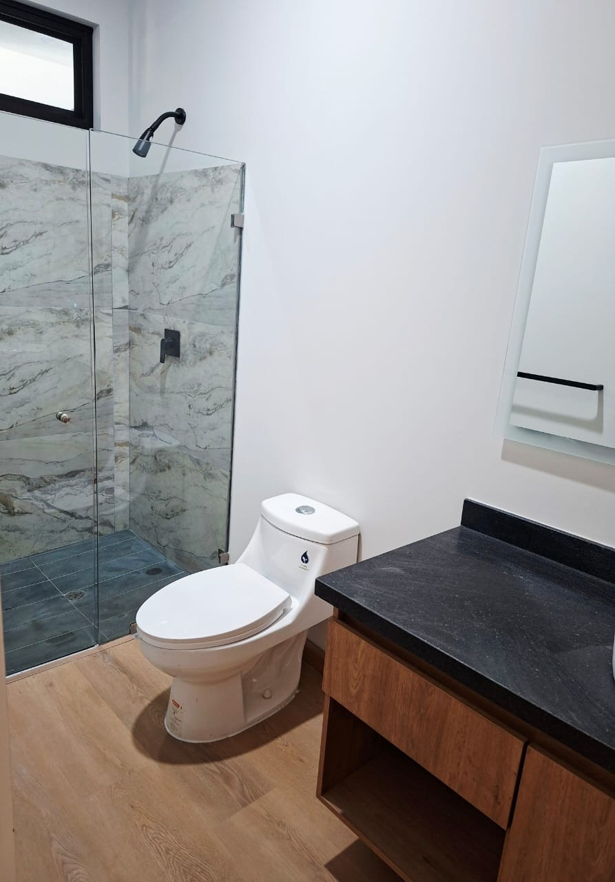 Baño con regadera de cristal y piso laminado